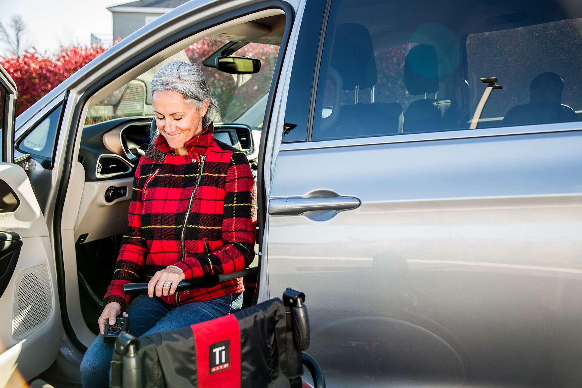 A woman sitting on the ASENTO while it raises her from the rocker panel up to the OEM seat